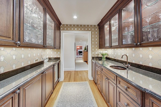 kitchen featuring sink, dark stone countertops, and light hardwood / wood-style floors