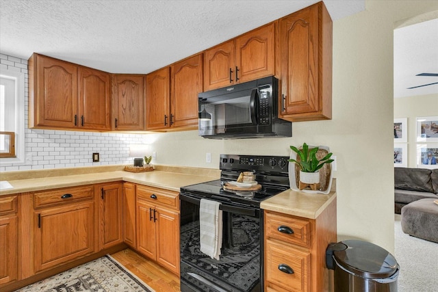 kitchen featuring a textured ceiling, black appliances, light hardwood / wood-style floors, and ceiling fan