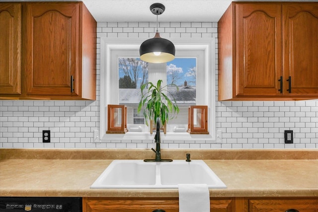 kitchen featuring decorative light fixtures, dishwasher, sink, and backsplash