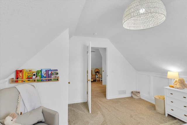 interior space featuring lofted ceiling, light colored carpet, and a textured ceiling