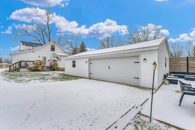 snow covered property with a garage and an outdoor structure