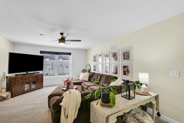 carpeted living room with a textured ceiling and ceiling fan