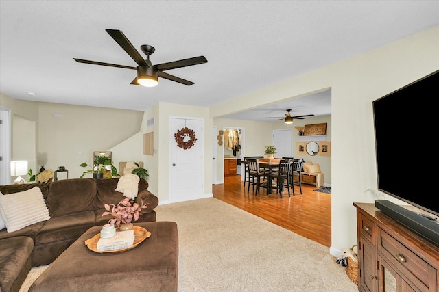 living room with ceiling fan, light carpet, and a textured ceiling