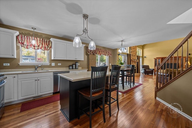 kitchen with dishwasher, hanging light fixtures, a center island, white cabinets, and sink