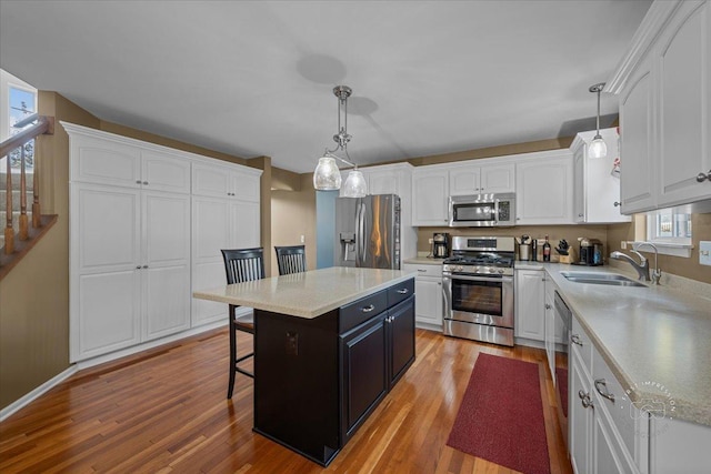 kitchen with a kitchen island, sink, appliances with stainless steel finishes, and hanging light fixtures