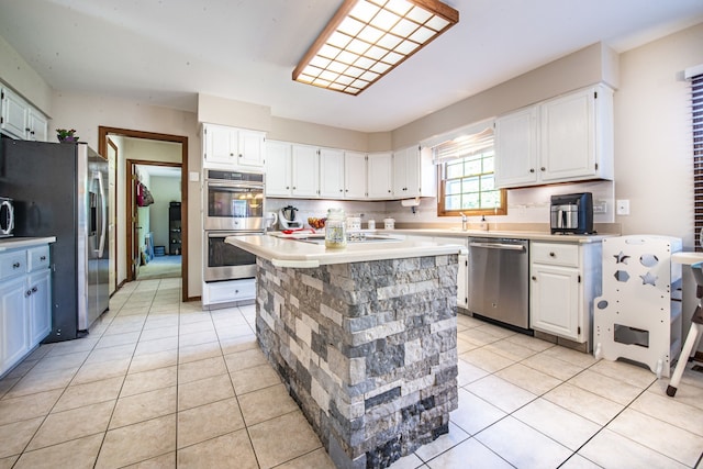 kitchen with light tile patterned flooring, a center island, white cabinetry, and appliances with stainless steel finishes