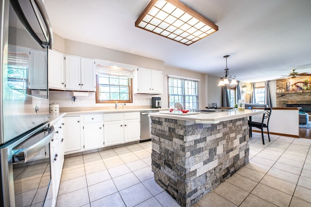 kitchen featuring appliances with stainless steel finishes, a center island, white cabinets, and hanging light fixtures