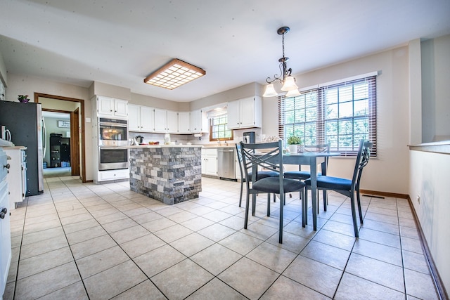 tiled dining space featuring a chandelier and plenty of natural light