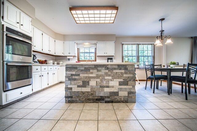 kitchen with decorative light fixtures, white cabinetry, a center island, stainless steel double oven, and backsplash