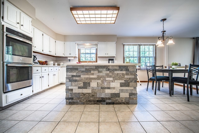 kitchen with decorative light fixtures, white cabinetry, a center island, stainless steel double oven, and backsplash