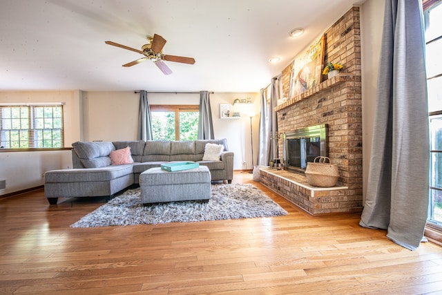 living room featuring wood-type flooring, a fireplace, and ceiling fan