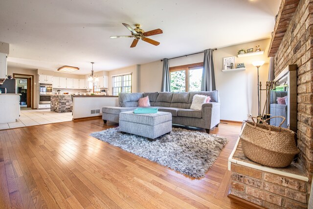 living room with light hardwood / wood-style floors and ceiling fan with notable chandelier