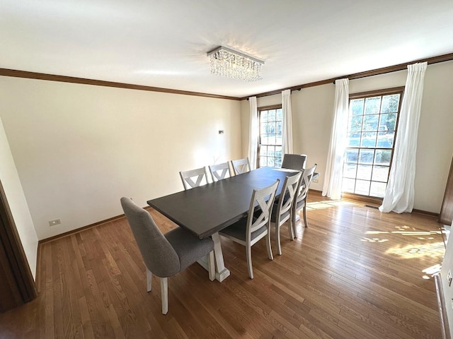 dining area with wood-type flooring, a chandelier, and crown molding