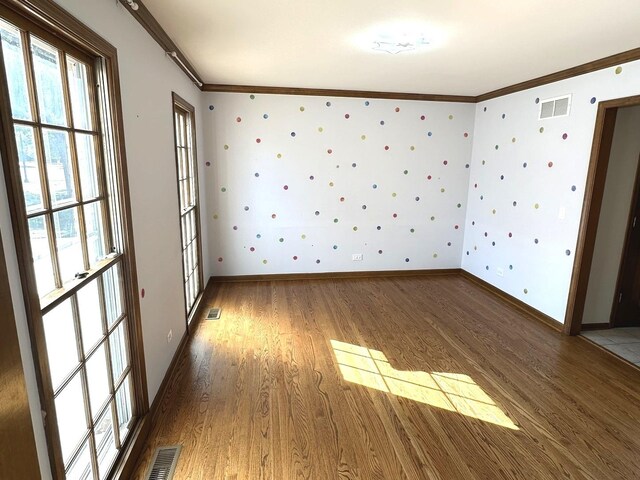 empty room with ornamental molding and hardwood / wood-style flooring