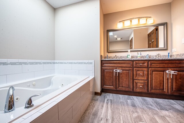 bathroom with vanity, tiled tub, and hardwood / wood-style floors