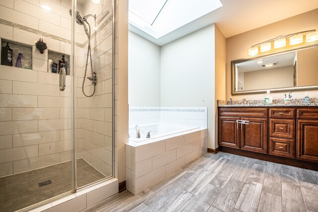 bathroom featuring shower with separate bathtub, a skylight, vanity, and wood-type flooring