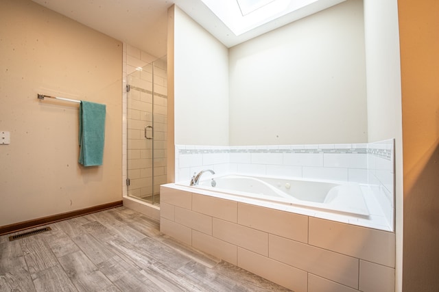 bathroom with independent shower and bath, a skylight, and hardwood / wood-style flooring