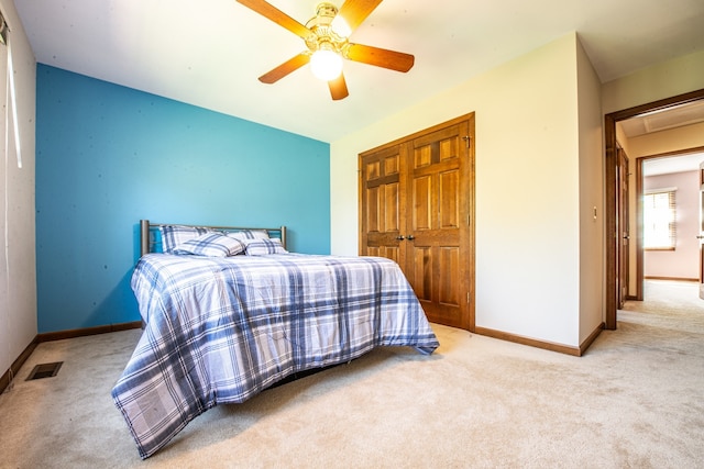 carpeted bedroom with ceiling fan and a closet