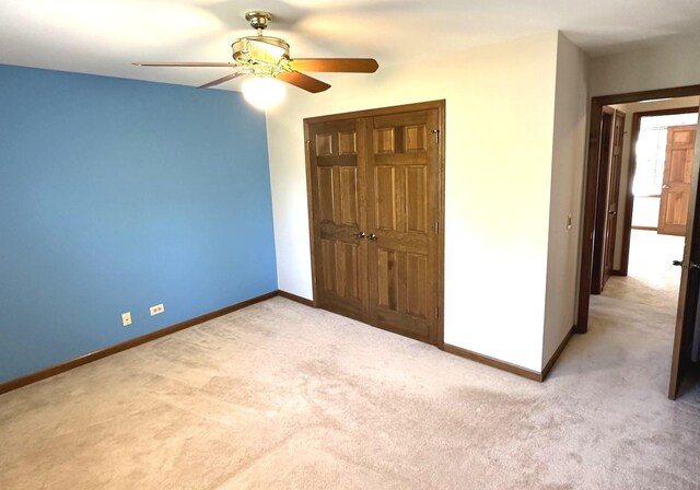 unfurnished bedroom featuring light carpet, a closet, and ceiling fan