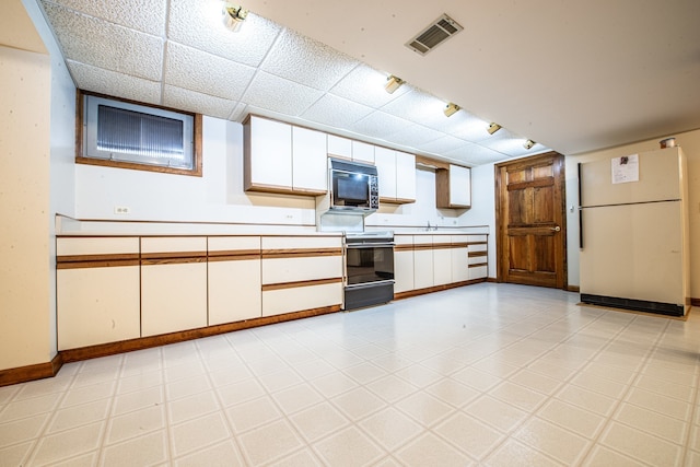 kitchen with white fridge, white cabinets, stainless steel range with electric cooktop, and a drop ceiling