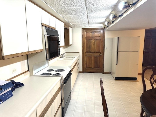 kitchen with white fridge, white cabinets, range with electric stovetop, and sink