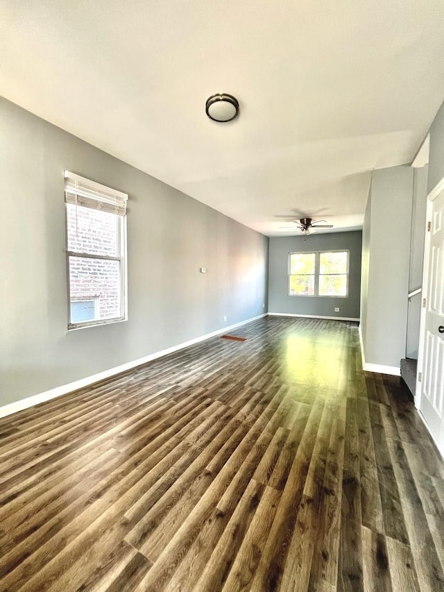 unfurnished living room with dark hardwood / wood-style flooring and ceiling fan