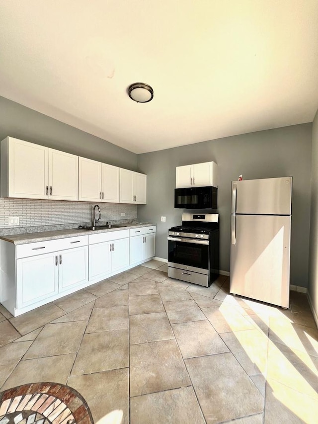 kitchen with sink, stainless steel appliances, tasteful backsplash, and white cabinetry