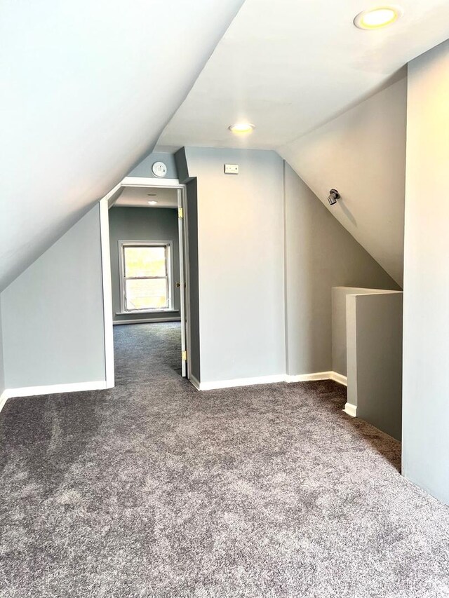 bonus room featuring lofted ceiling and dark carpet