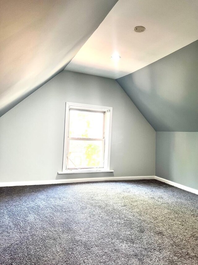 bonus room featuring lofted ceiling and dark carpet