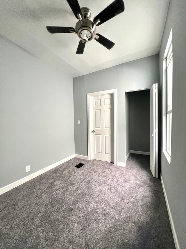 unfurnished bedroom featuring ceiling fan and dark carpet