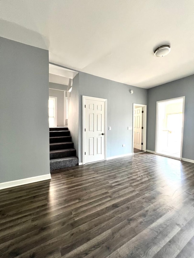 unfurnished living room with dark hardwood / wood-style flooring and plenty of natural light