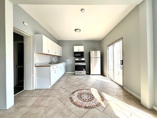 kitchen with refrigerator, tasteful backsplash, white cabinets, stainless steel range with gas stovetop, and sink