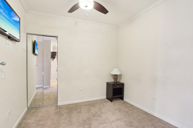 unfurnished bedroom featuring a closet, ceiling fan, light colored carpet, and ornamental molding