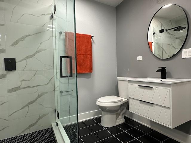 bathroom featuring vanity, tile patterned flooring, a shower with door, and toilet