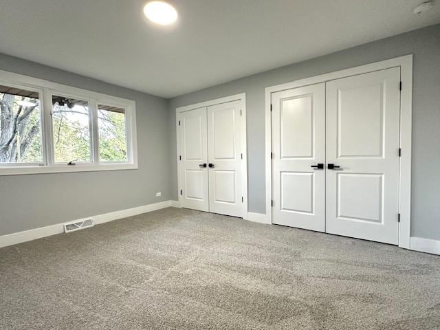 unfurnished bedroom with two closets and carpet floors