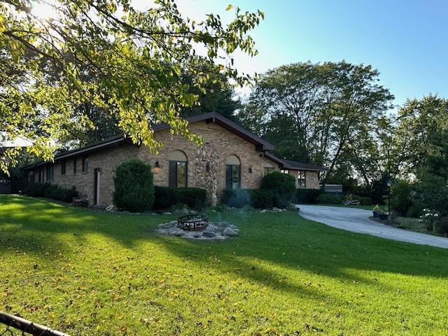 view of side of home with a yard and a fire pit