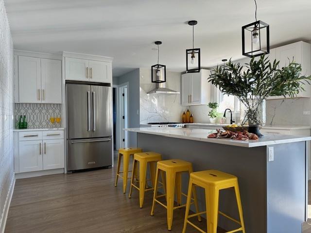 kitchen featuring high quality fridge, a breakfast bar, and white cabinets