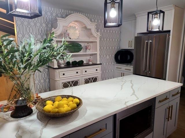 kitchen with pendant lighting, gray cabinets, high end fridge, white cabinetry, and light stone counters