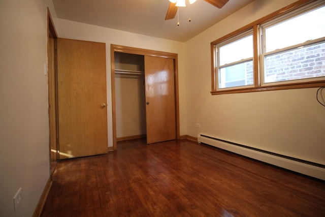 unfurnished bedroom featuring ceiling fan, baseboard heating, a closet, and dark wood-type flooring