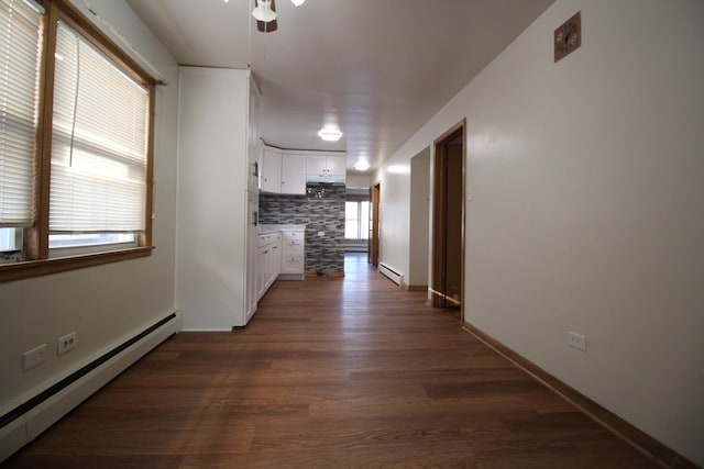 corridor featuring baseboard heating and dark hardwood / wood-style flooring