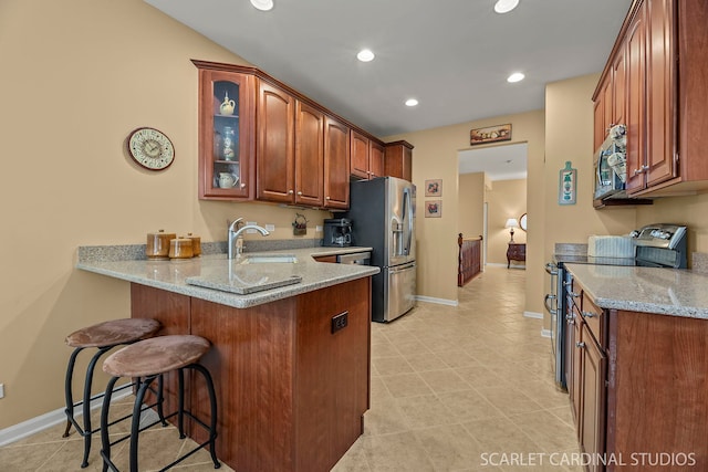 kitchen with light stone counters, stainless steel appliances, kitchen peninsula, and a breakfast bar