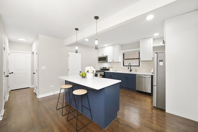 kitchen with stainless steel appliances, a center island, white cabinetry, decorative light fixtures, and backsplash