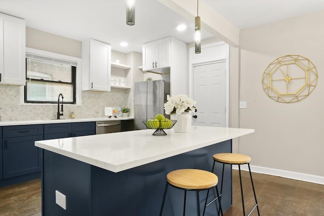 kitchen featuring appliances with stainless steel finishes, dark hardwood / wood-style floors, hanging light fixtures, and white cabinetry