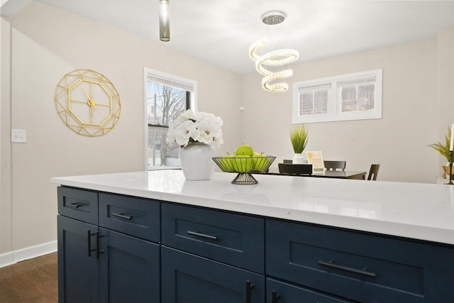 kitchen featuring dark hardwood / wood-style flooring, light stone countertops, an inviting chandelier, and pendant lighting