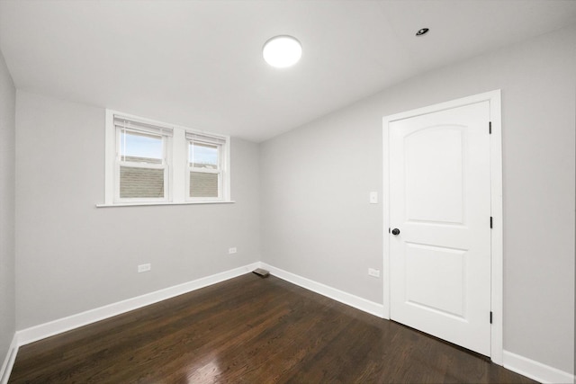 spare room featuring dark hardwood / wood-style flooring and lofted ceiling