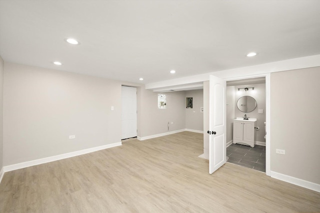 basement with sink and light hardwood / wood-style floors