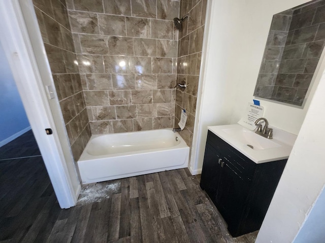 bathroom with hardwood / wood-style flooring, tiled shower / bath combo, and vanity