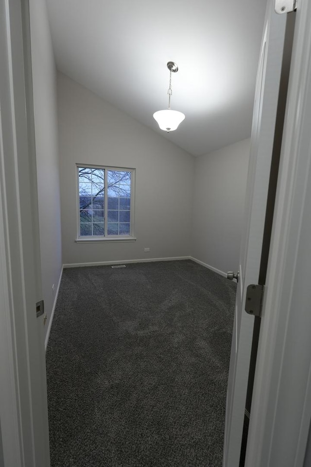 empty room with vaulted ceiling and carpet flooring