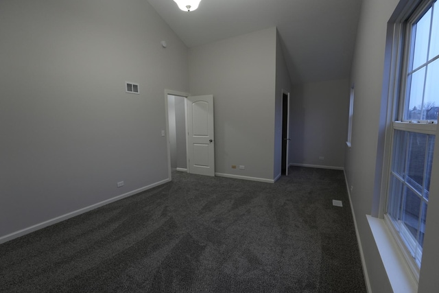 empty room with high vaulted ceiling and dark carpet