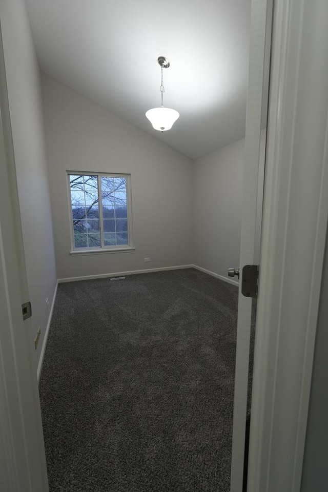 spare room featuring lofted ceiling and dark colored carpet